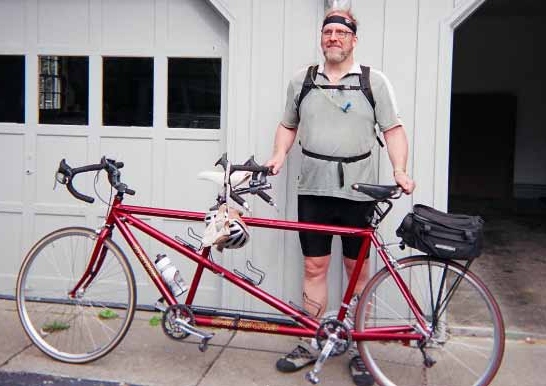 Mark Remaly standing next to a red tandem bike.